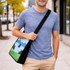 A custom sublimation crossbody bag with a scenic design in blue and green, displayed on a person walking outdoors.