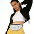 A model poses with a holographic bum bag featuring a logo, styled with a black jacket and yellow trousers.