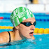 A green and white striped silicone swim cap for women, designed for long hair, worn by a swimmer in a pool setting.