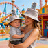 A grey bucket hat with a logo, worn by a woman holding a child, both featuring plush koala toppers.