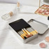 A metal box set containing 12 makeup brushes with silver handles and gold detailing.