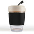 A reusable coffee cup featuring a transparent body, a beige lid with a straw, and a black silicone band for grip.