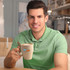A wheat fibre cup in a light color with a matching spoon, held by a smiling man in a green polo shirt.