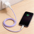 A purple 100W fast charging cable connected to a wall charger and an iPhone on a wooden surface.