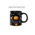 A black ceramic coffee mug featuring a spooky Halloween design with skeletons, bats, and a smiling pumpkin spinner toy.