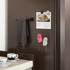 Paw shape clog shoe fridge magnets in pink and white, displayed on a dark fridge alongside a towel and an image.