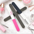 Three triple-sided nail files in pink, grey, and dark blue, arranged on a flat surface with beauty products around.