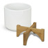 A white planter with a bamboo base sits beside it, featuring a simple, modern design.
