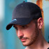 A dark grey cap with a curved brim and a logo on the front, worn by a male model.