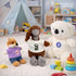 A plush doll wearing a white T-shirt, alongside a koala and a fox in colourful outfits, with toys in the background.