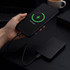 A power bank and a smartphone connected by a charging cable, featuring a green charging indicator. The power bank is black.