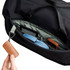 A close-up of a black duffel bag's interior, featuring a blue headset, a gadget, and a brown leather keychain.
