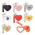 A heart-shaped compact mirror with a keychain, featuring various coloured designs and logos in pink, black, white, red, and yellow.
