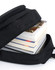 A black backpack partially open, revealing several stacked books inside. The backpack features a zip closure and a simple design.