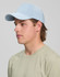 A light blue 5-panel cap with a curved brim, worn by a young man dressed in a beige shirt. The cap has a logo.