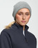 A grey knit beanie worn by a model, featuring a rolled-up cuff, alongside a dark fleece jacket.