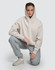 A unisex premium fleece oversized hoodie in light grey, worn by a model with grey tracksuit bottoms and sneakers.