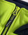 A close-up of a bright yellow zipper on a hooded puffer vest with a navy fleece lining. It has a branding logo.