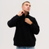 A model wearing a black Everest Polar Fleece 1/4 zip jumper, adjusting the collar. The garment has a logo.