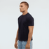 A man wearing a navy blue t-shirt stands in profile against a plain background. The shirt features a logo.