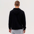 A black zip hood with a hooded design, viewed from the back, worn over grey pants. It has a logo on the clothing.