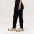 Black track pants featured alongside a person wearing gold sneakers, with a simple, neutral background.