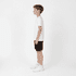 Youth Core Shorts in black, worn by a model standing sideways, paired with a white t-shirt and white sneakers.