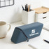 A blue silicone pen holder with a zip, displaying a logo, placed on a desk with stationery and a mug.