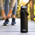 A drink bottle in matte black with a flip straw, featuring a handle and branding.