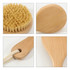 A round body brush with a short wooden handle and natural bristles, featuring a hanging loop for easy storage.