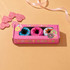A pink gift box with a rectangular window displays brightly coloured donut-shaped socks inside.