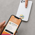A hand holding a phone near a white smartphone featuring a colourful NFC doming epoxy sticker.