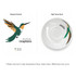 A coffee mug featuring a green and orange hummingbird design with a glossy white finish and a logo on one side.