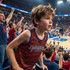 A youth active tank top in red and blue worn by a boy at a sporting event, surrounded by cheering fans.