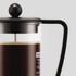 A French press with a black lid and handle, featuring a glass body and brewed coffee inside.