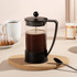A Bodum Brazil French Press in black, filled with coffee, set on a cork mat, with a spoon and pastries in the background.