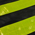 A close-up of a gourd-shaped hi-vis reflective safety vest with black mesh and bright yellow reflective strips.