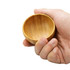 A bamboo bowl held in a hand, featuring a smooth, natural texture and circular shape.