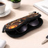 A black neoprene glasses pouch with vibrant indigenous patterns, containing a pair of sunglasses, placed on a desk.