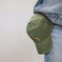 A vintage washed cap in green with a logo, resting against denim jeans.
