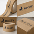 Kraft paper packaging tape featuring a logo and a brown colour. Includes images of tape on a roll and applied to boxes.