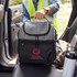 A grey cooler bag with a logo, placed on the seat of a vehicle, alongside a drink bottle.