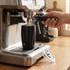 A drink bottle with a sleek black design and a branding logo, positioned under an espresso machine.