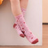 A pair of pink knitted kids' socks featuring heart patterns and a reddish band at the top, resting on a white surface.