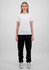 A woman in a white t-shirt and black track pants stands against a plain background. The pants have a branding logo.