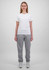 A woman wears a plain white t-shirt and grey track pants, standing against a light grey background. The pants have a logo.