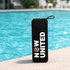 A black portable speaker with a round logo, sitting by a blue pool.