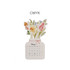 A floral-themed desk calendar featuring a vase design with assorted flowers, predominantly in pastel colours.