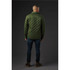 A green quilted jacket viewed from the back, featuring a collar and a logo. Worn with dark jeans and boots.