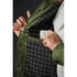 A quilted jacket featuring an olive green exterior and a checkered interior, with someone placing a phone in the inner pocket.